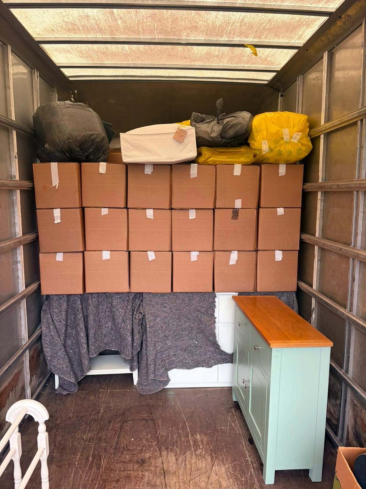 Neat wall of boxes above blanket-wrapped furniture inside a Luton van