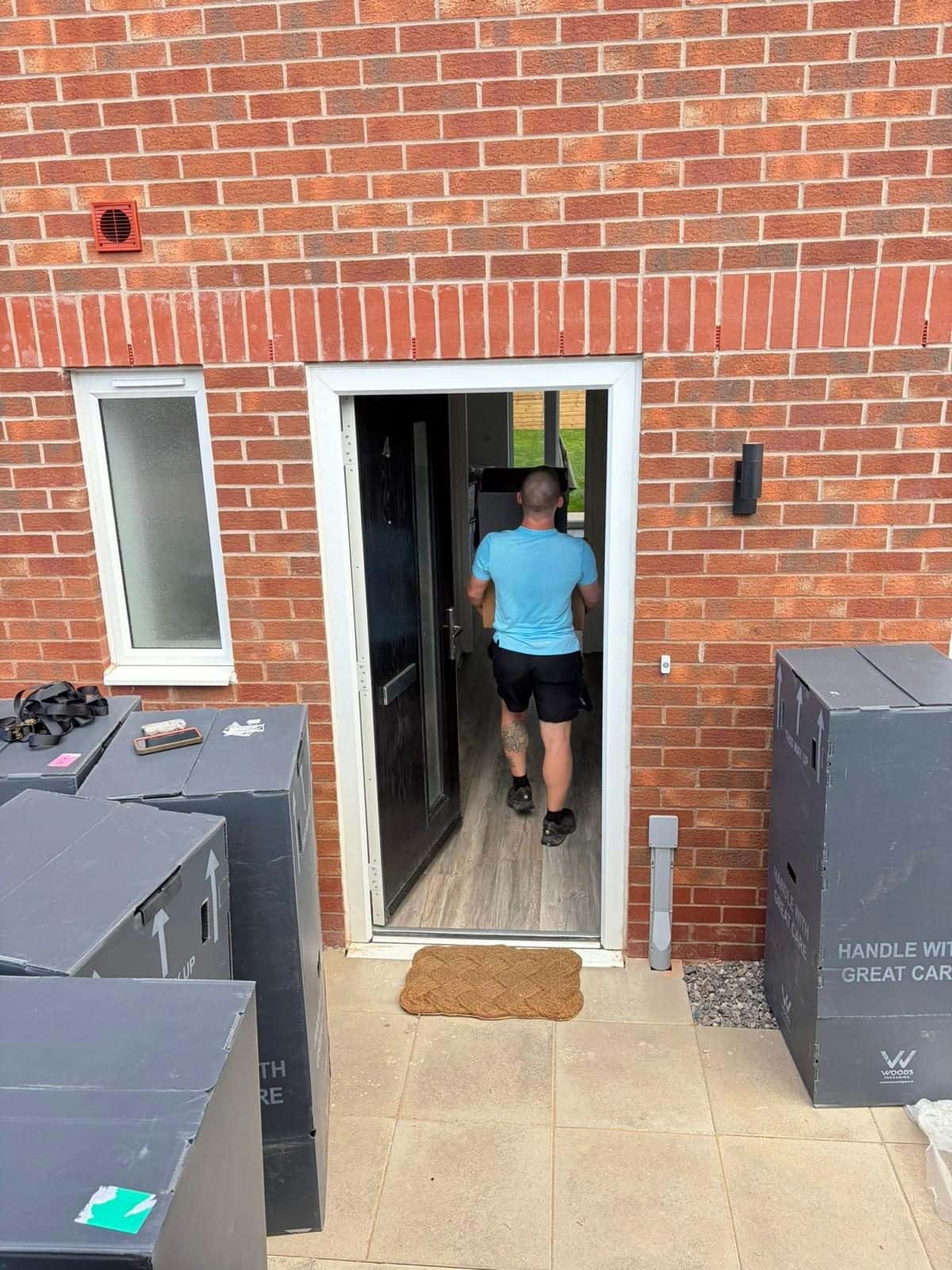 Duffield crew member carrying a box into a new-build home past wardrobe cartons