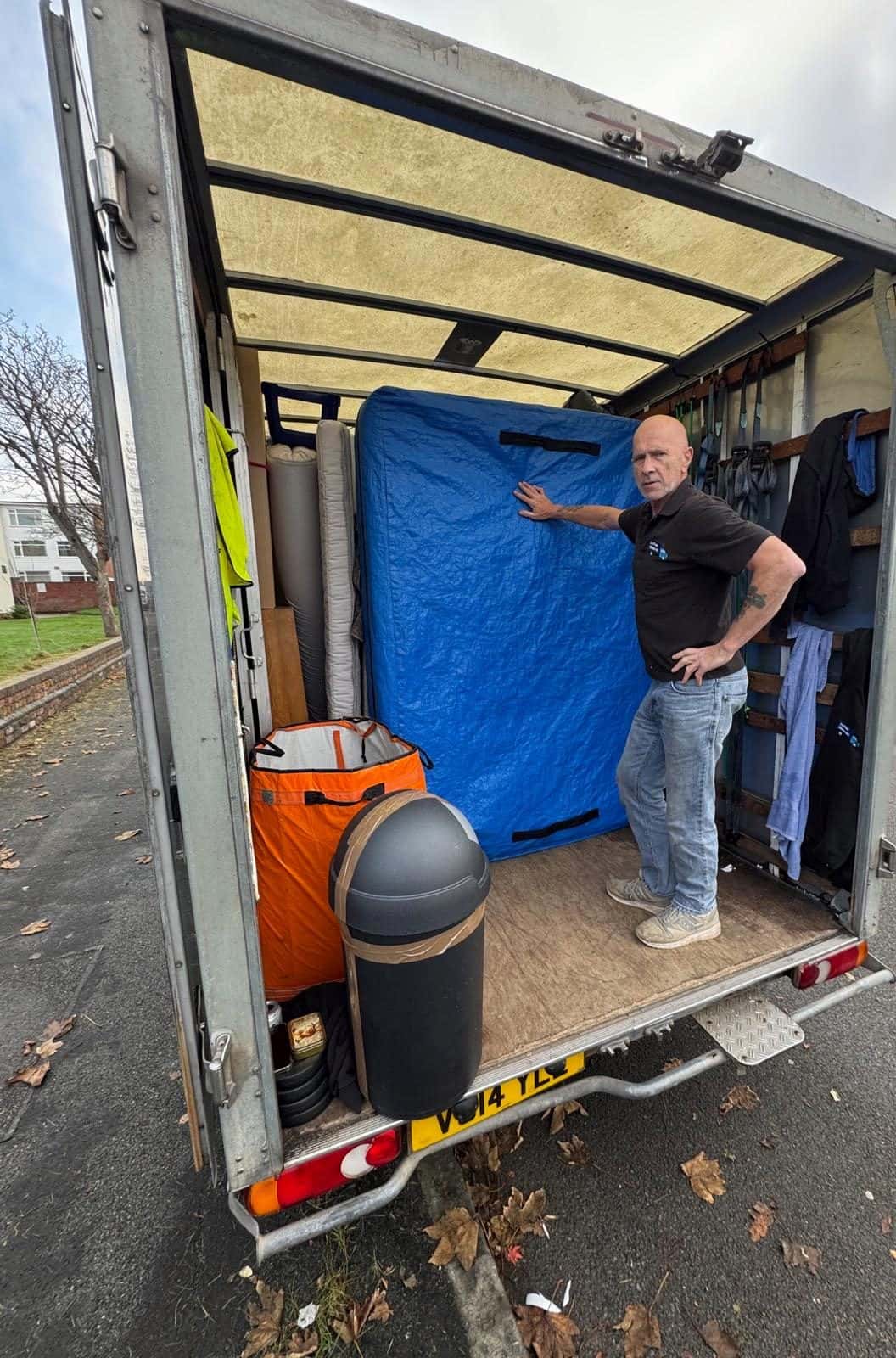 Duffield crew member in a van next to a wardrobe in a blue quilted cover