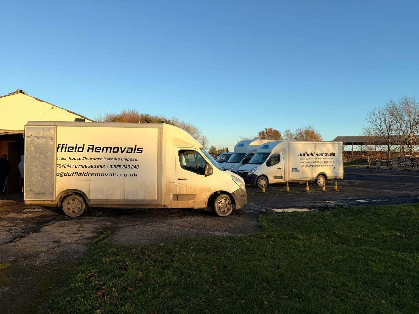 Duffield Removals vans lined up in a yard in evening sun