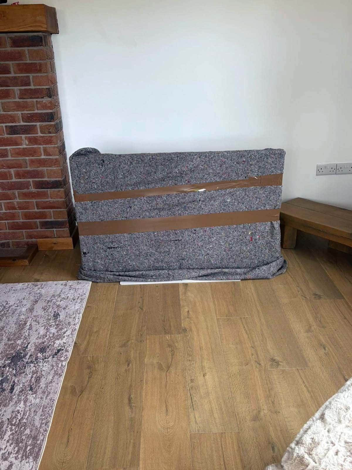 TV or mirror wrapped in a grey felt blanket and tape against a wall