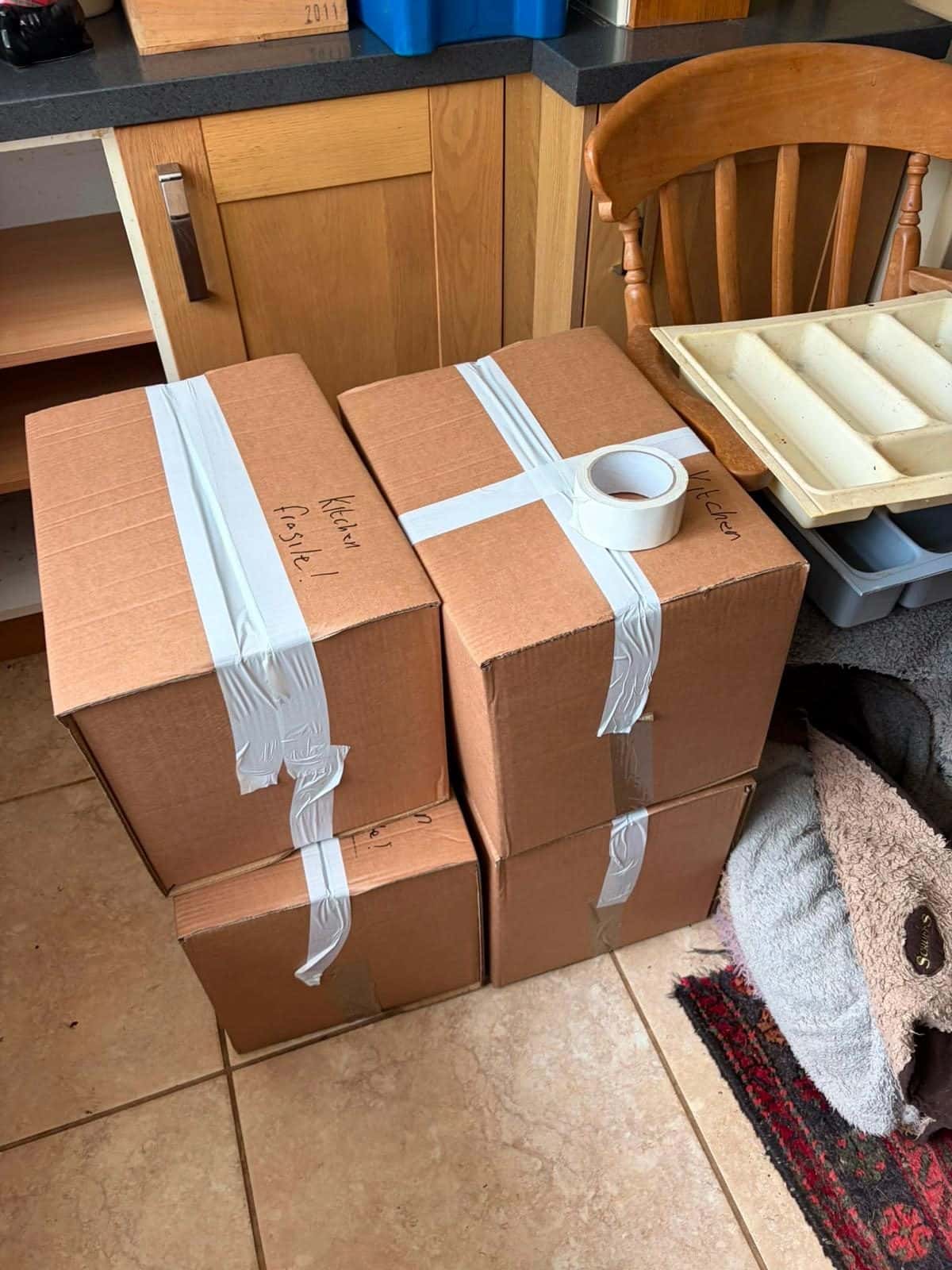 Boxes taped and marked kitchen fragile on a tiled floor