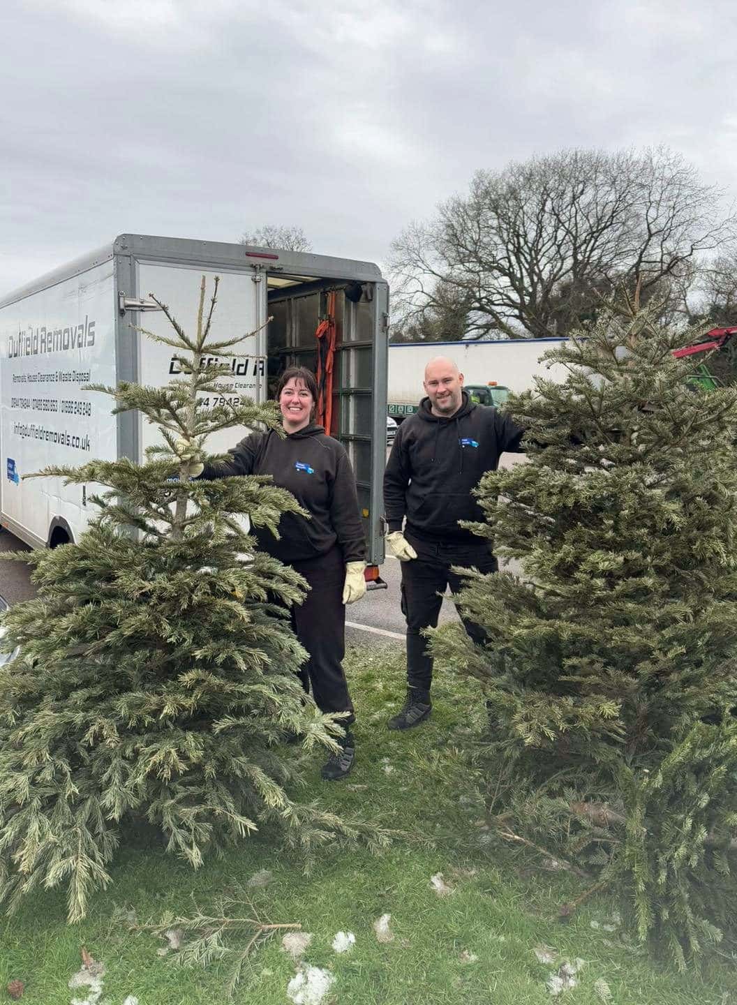 Leanne and a Duffield crew member standing with two Christmas trees