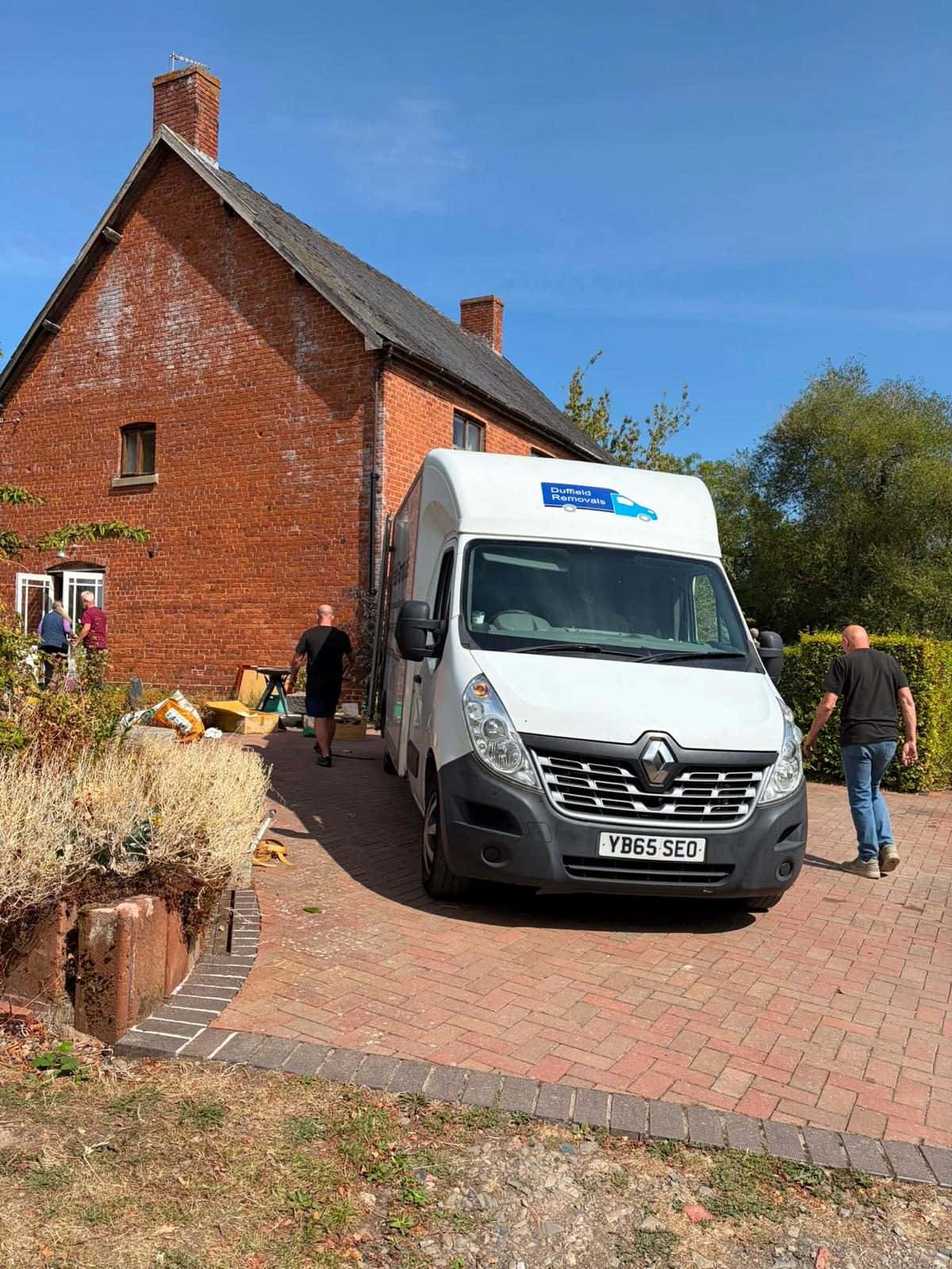 Duffield crew walking to a red-brick farmhouse on moving day