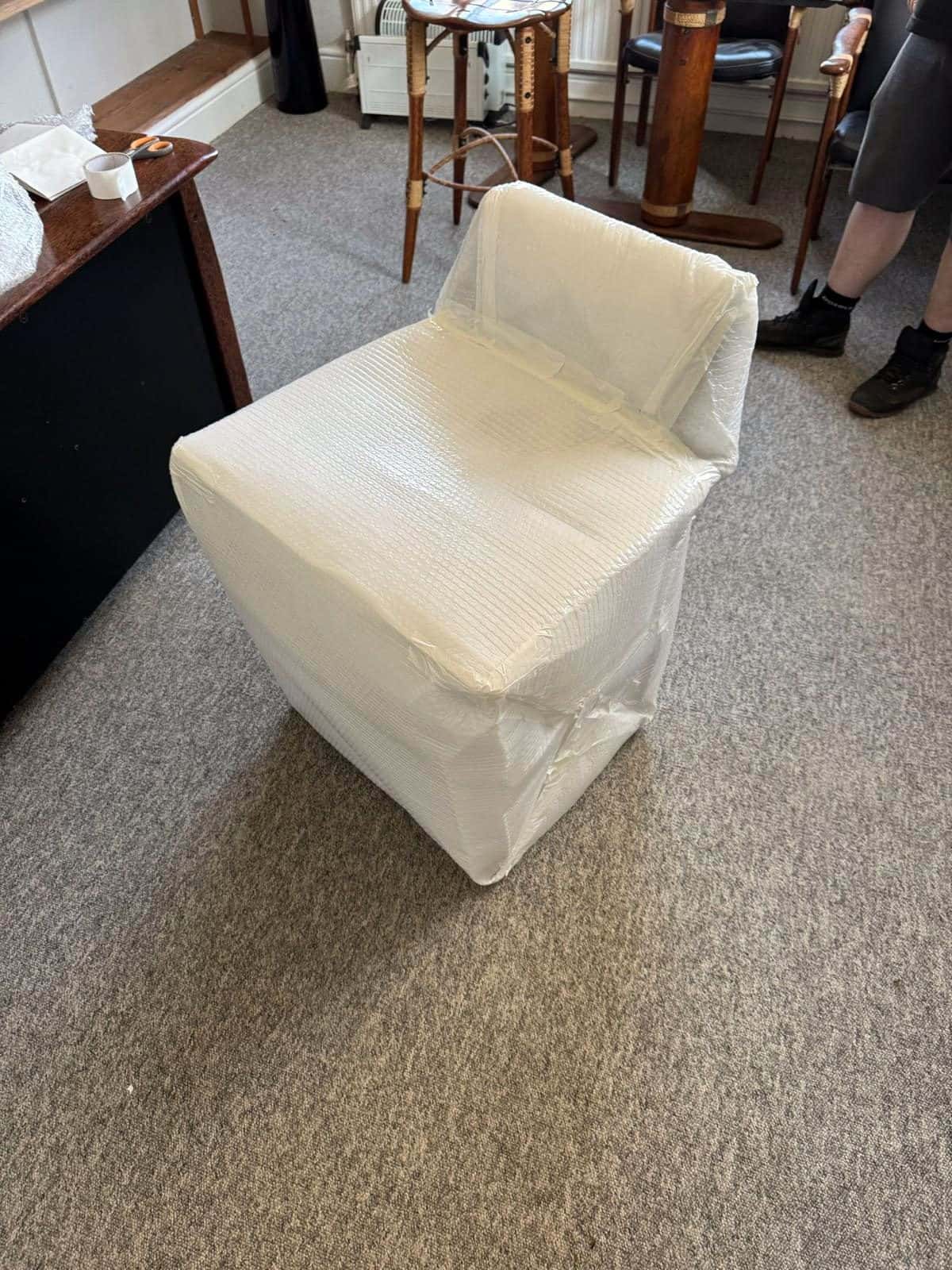 Office chair bubble-wrapped on the carpet during an office move
