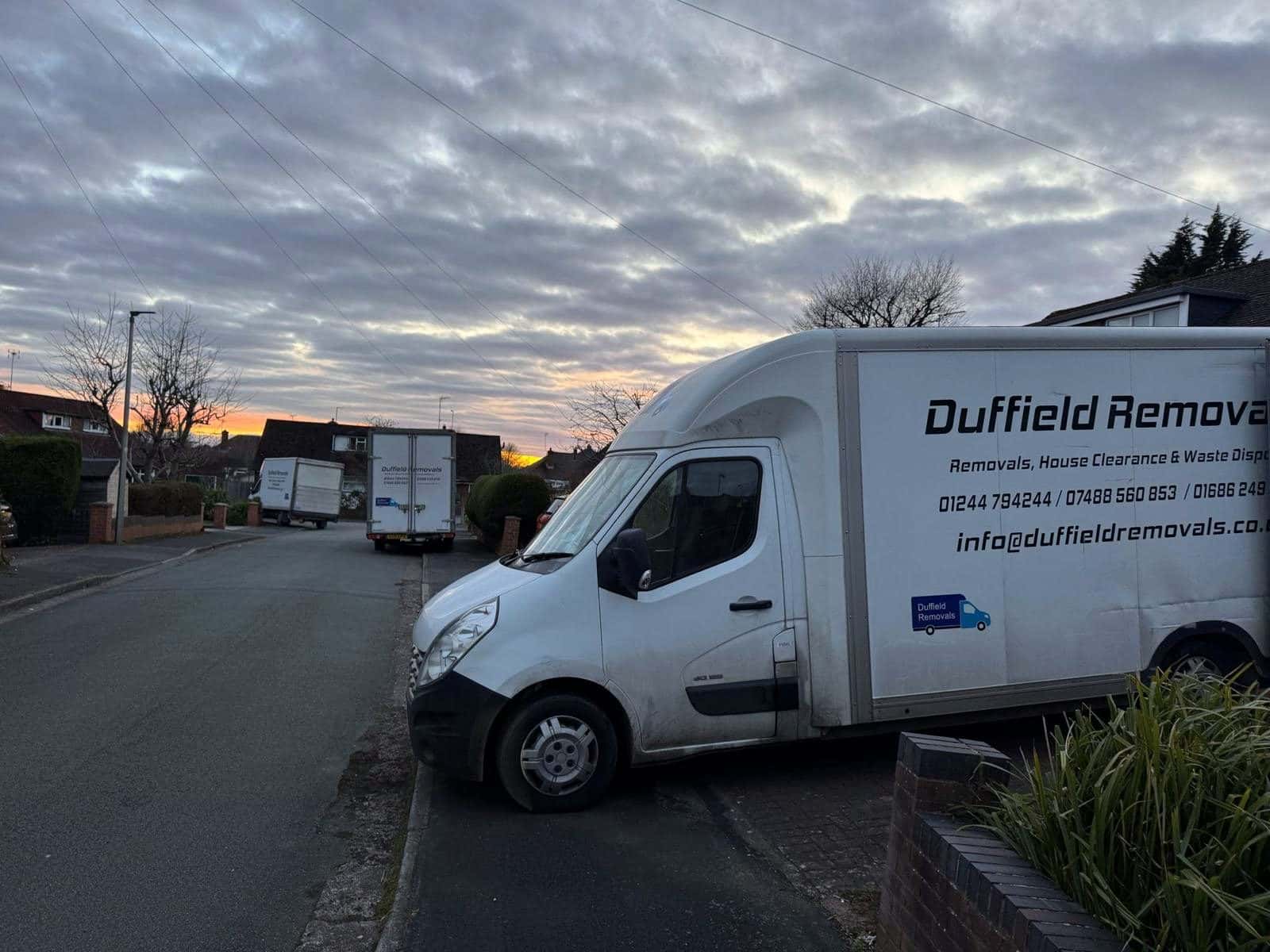 Duffield Removals vans on a residential street at sunrise