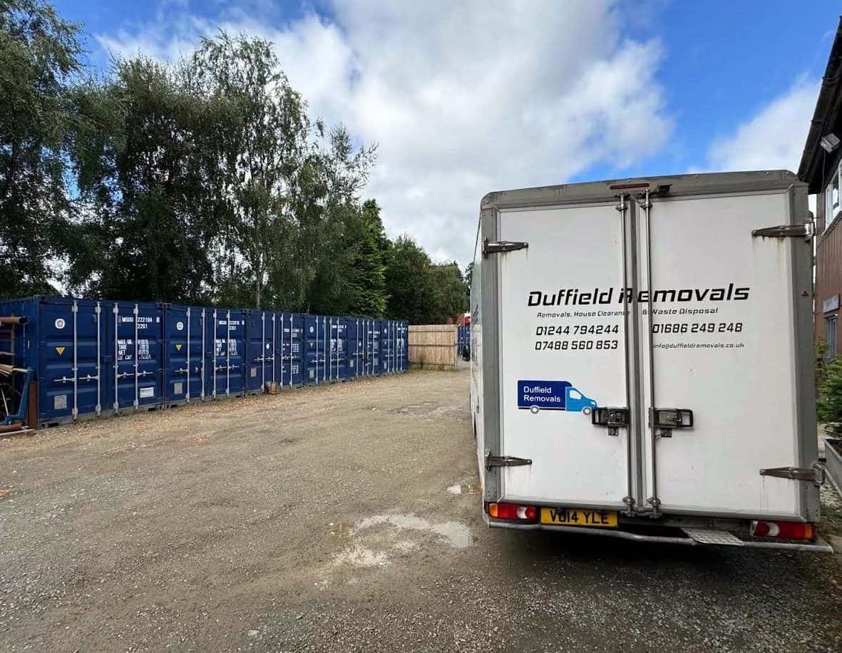 Row of blue storage containers at the Rhayader yard with a Duffield van