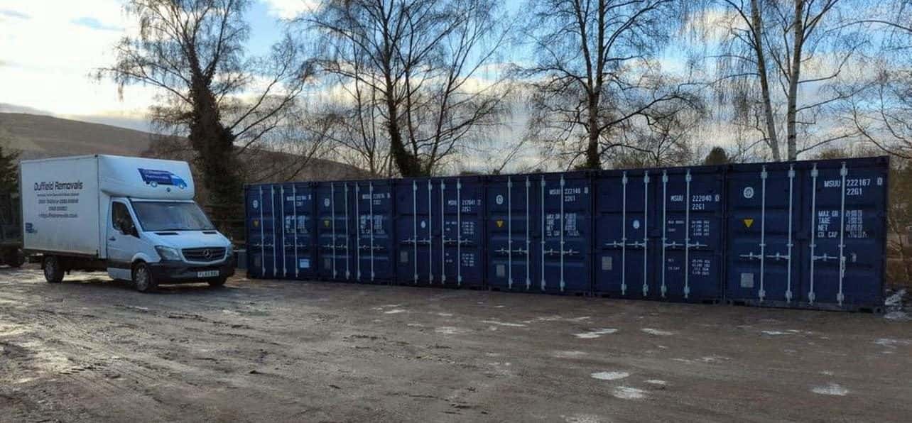 Long row of blue storage containers and a Duffield van at Rhayader in winter