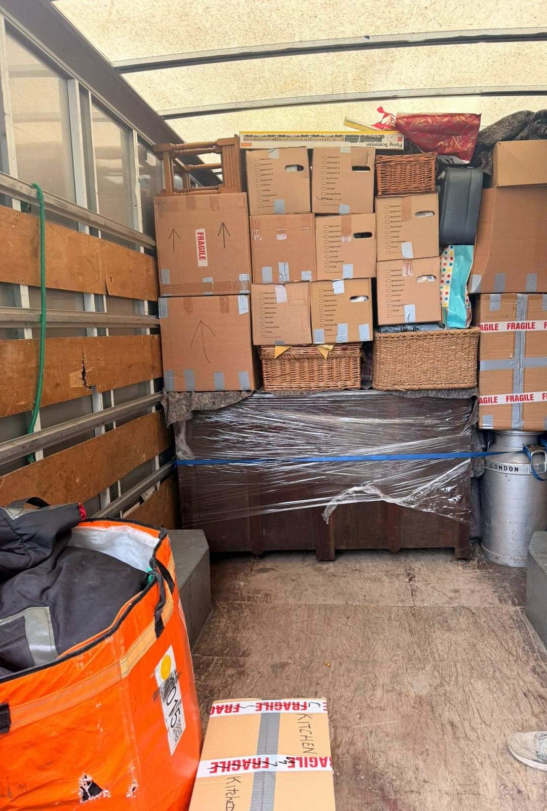 Room-labelled cartons and a stretch-wrapped chest strapped inside a van