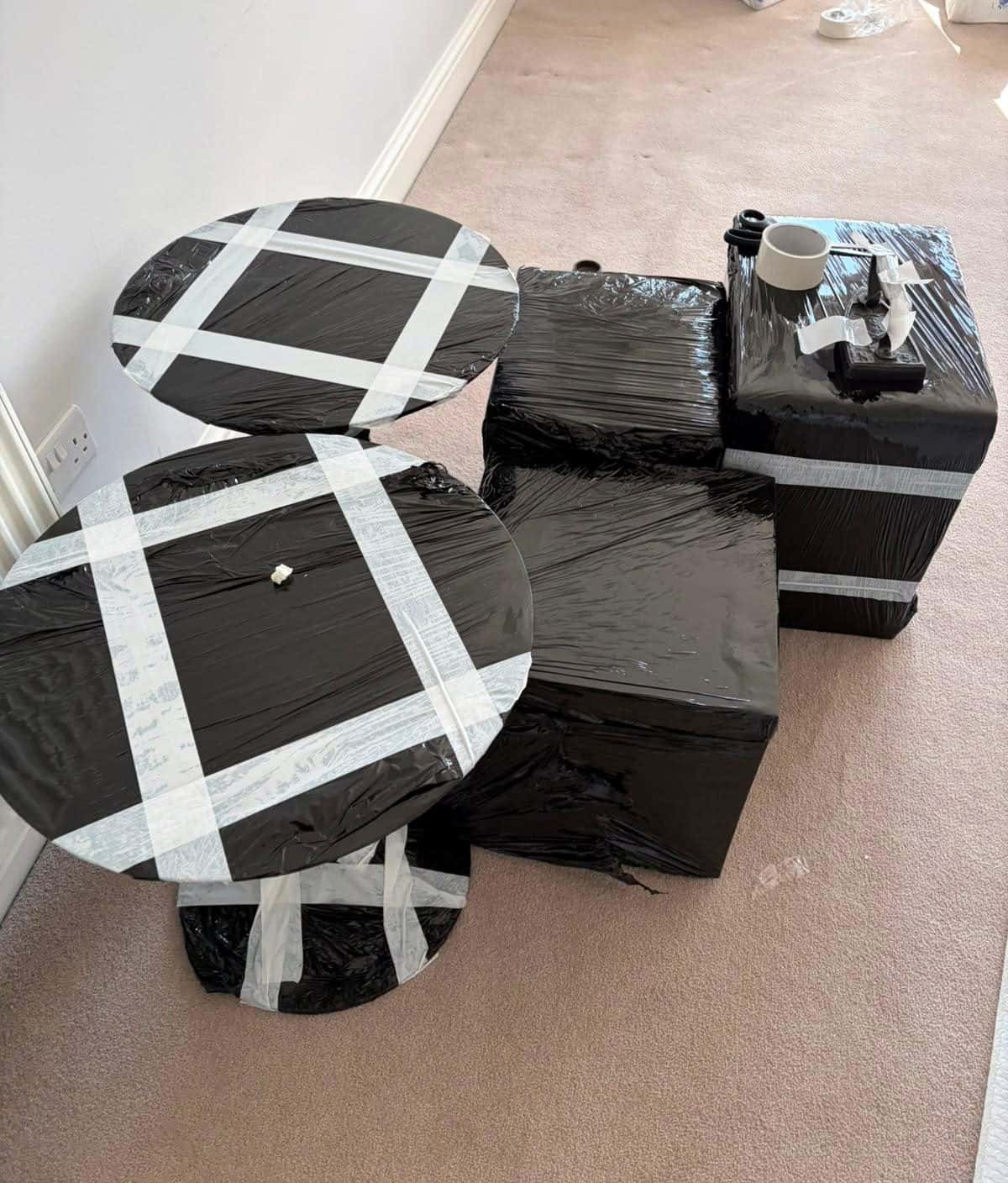 Round side tables and cubes wrapped in black stretch film with tape crosses