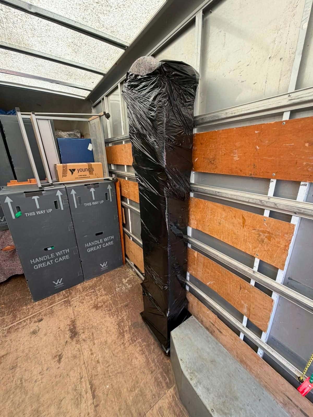 Tall item stretch-wrapped beside wardrobe cartons in a van