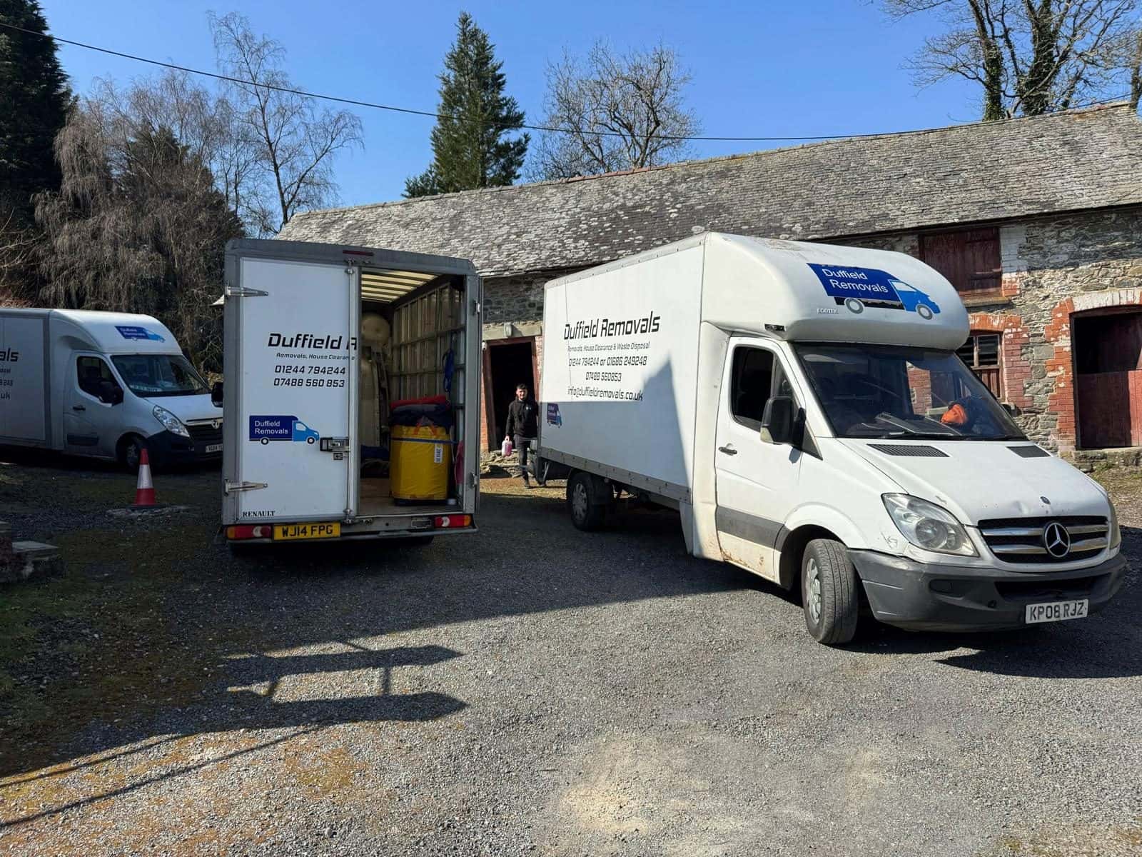 Three Duffield vans at a stone barn, one open and loaded