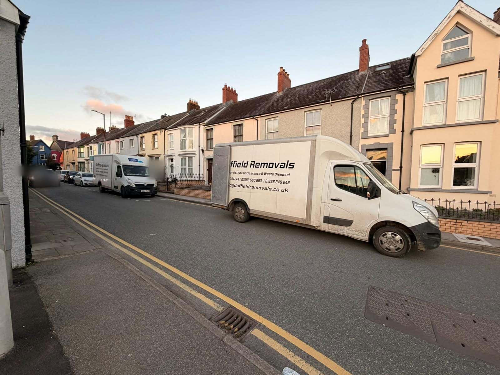 Two Duffield Luton vans on a terraced street with double yellow lines