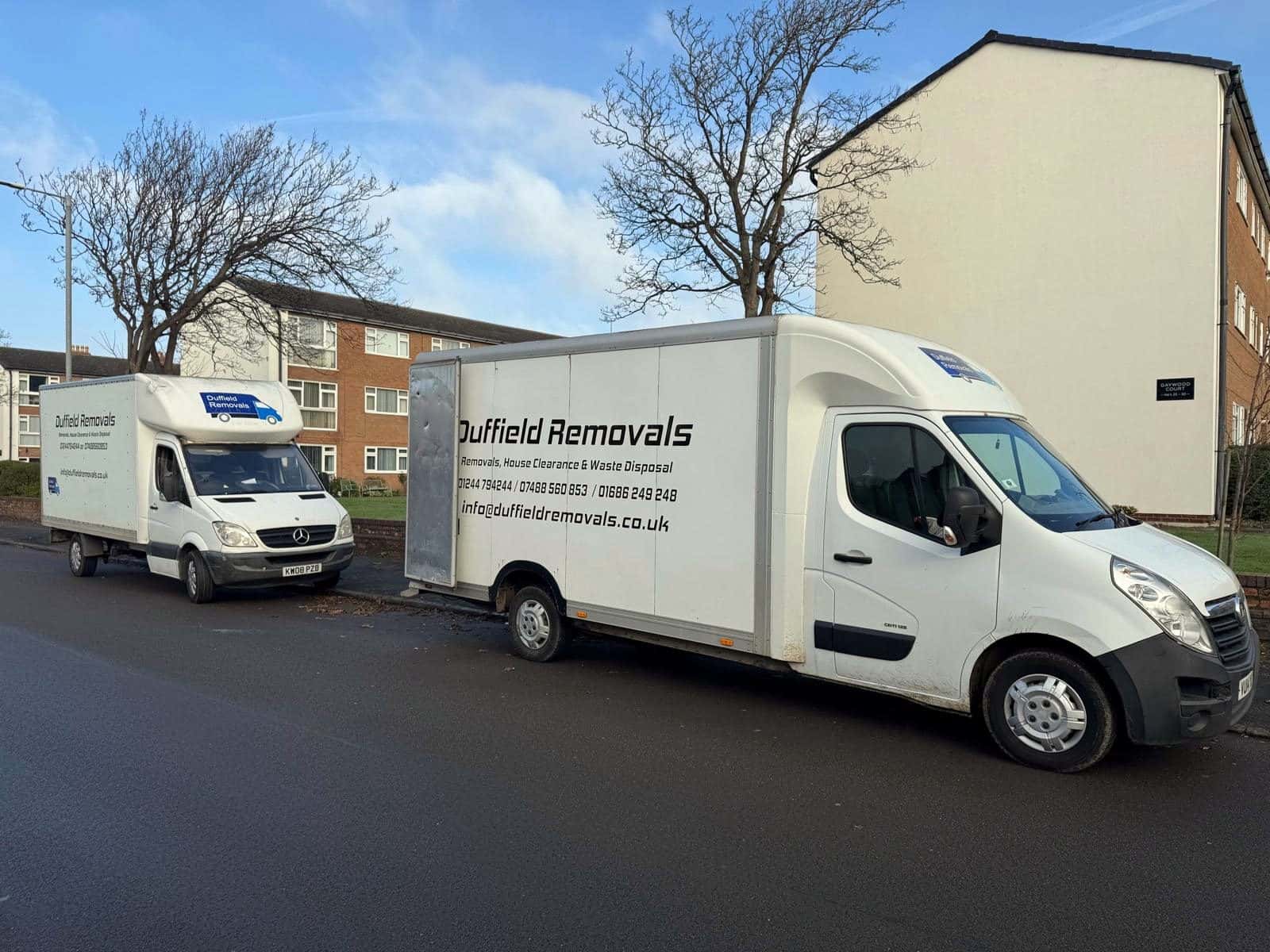 Two Duffield Luton vans parked outside a three-storey block of flats