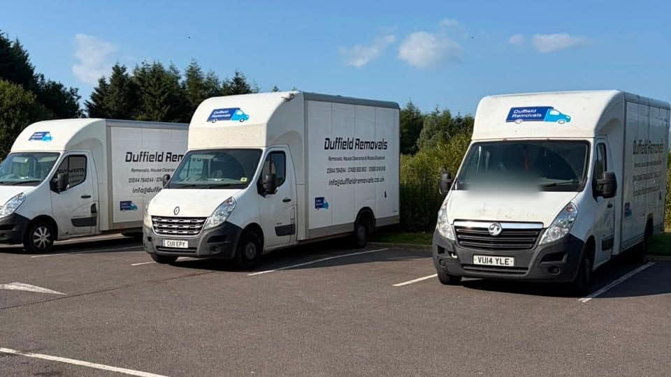 Three Duffield Removals Luton vans parked side by side under a clear blue sky