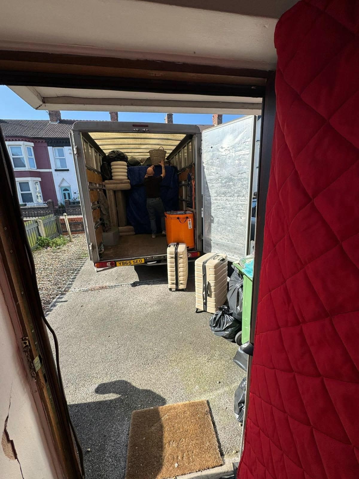 Doorway draped with a red quilted cover while a Duffield van is loaded outside