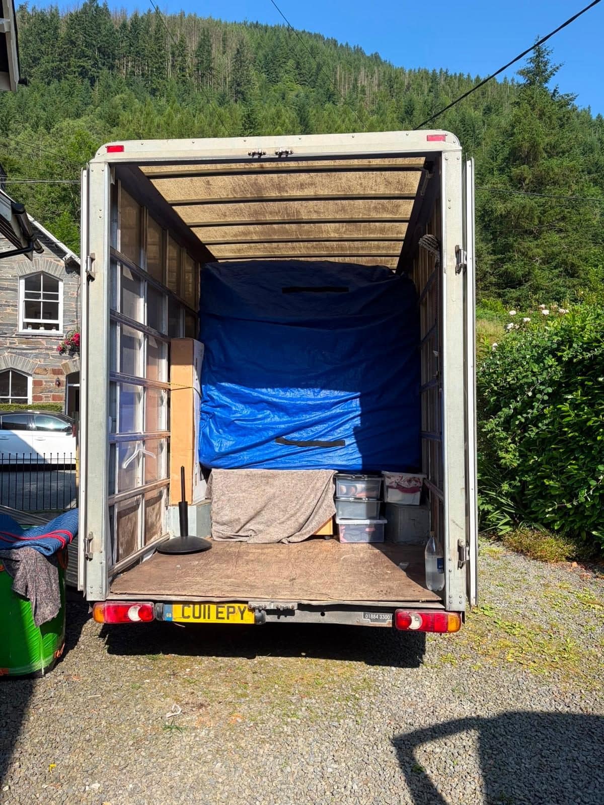 Open Duffield van with a tarp-covered load in a wooded valley