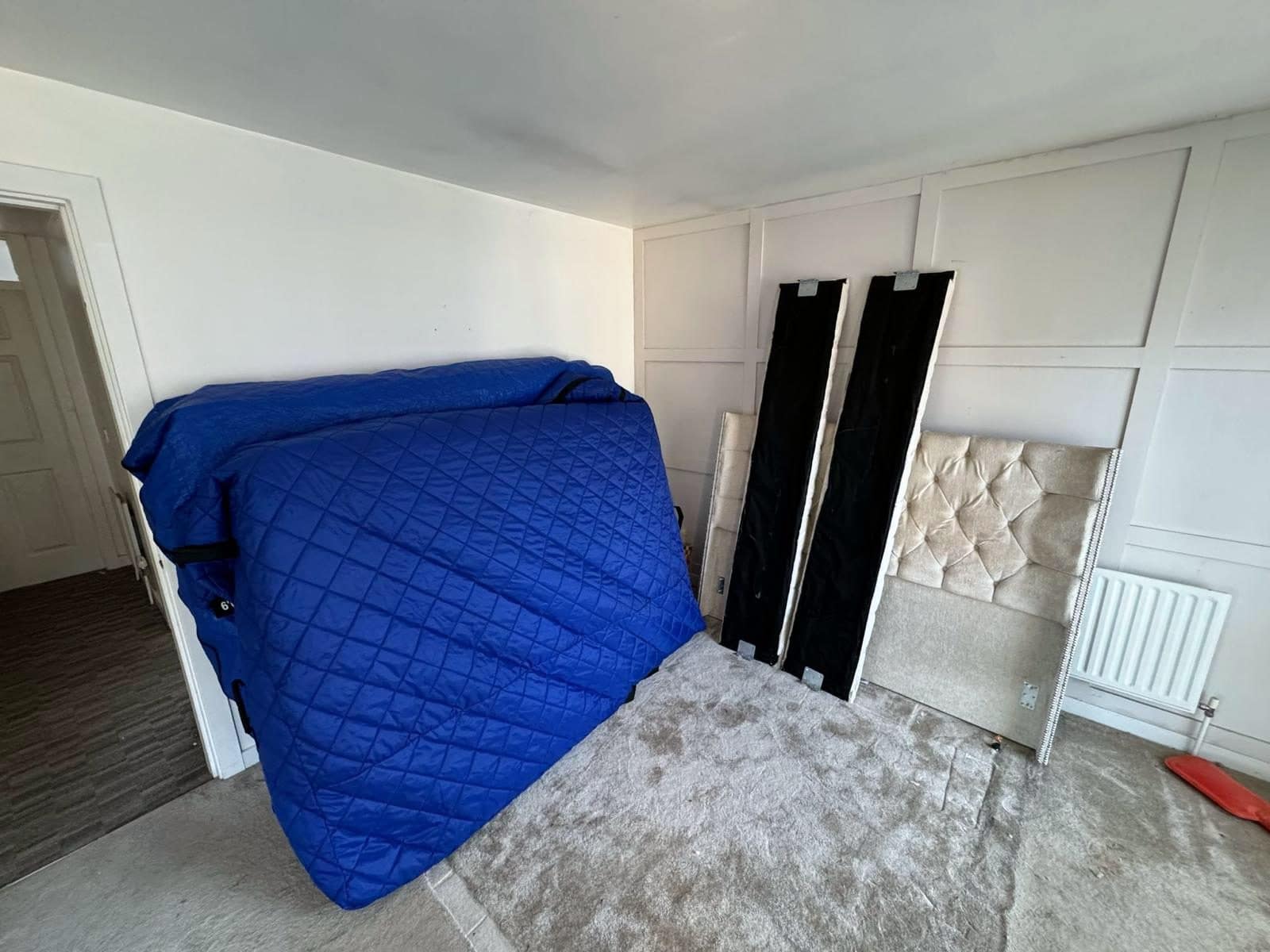 Mattress in a blue quilted cover with the dismantled bed frame beside it