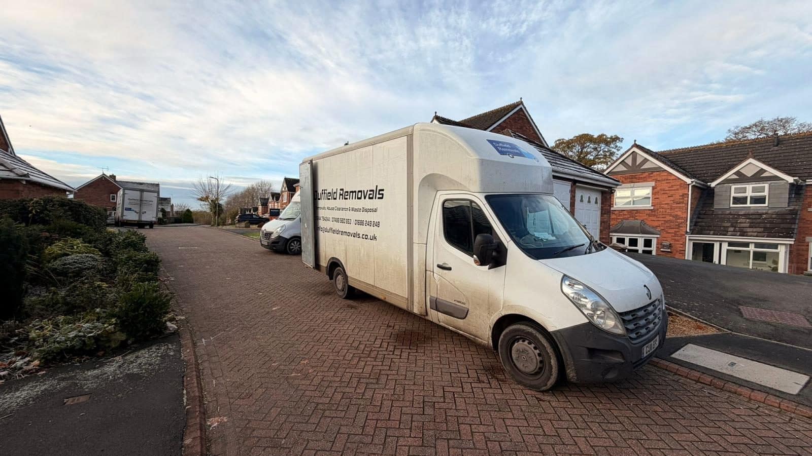 Duffield Removals Luton van on a block-paved drive with two more vans in the street