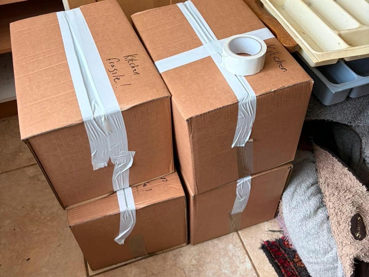 Taped boxes marked kitchen fragile on a tiled floor, ready for moving day