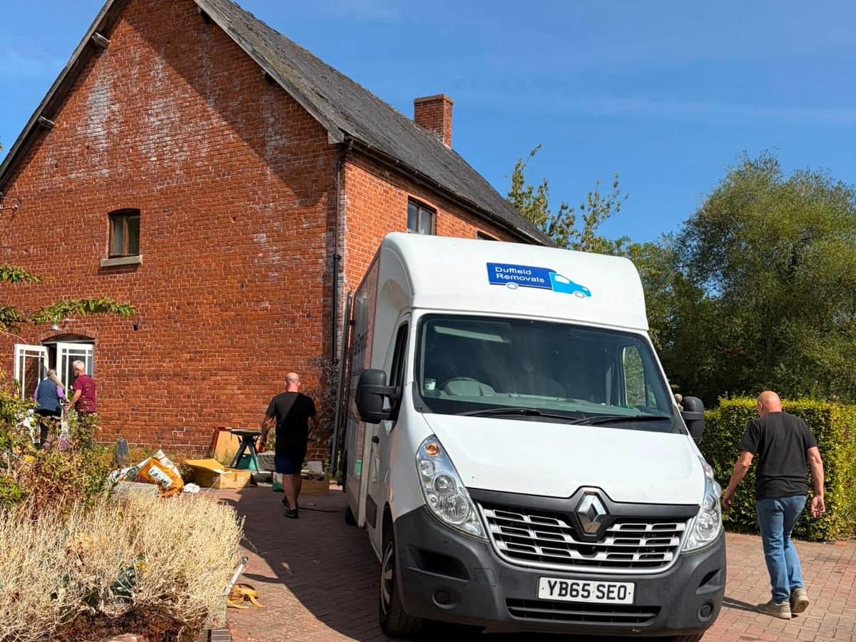 Duffield crew walking up to a red-brick farmhouse on moving day, Luton van on the drive