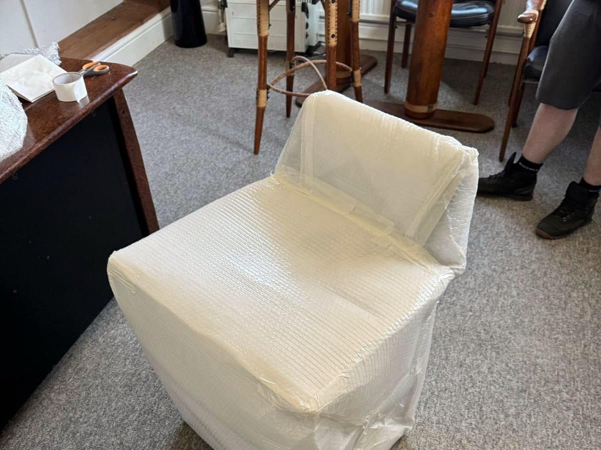 Office chair fully bubble-wrapped on the carpet before an office removal