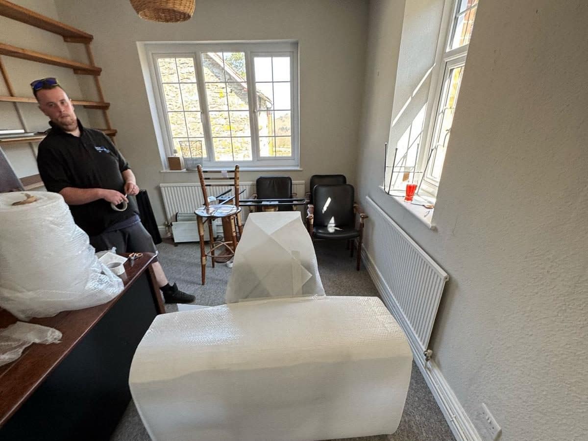 Duffield crew member wrapping office furniture in bubble wrap during an office move