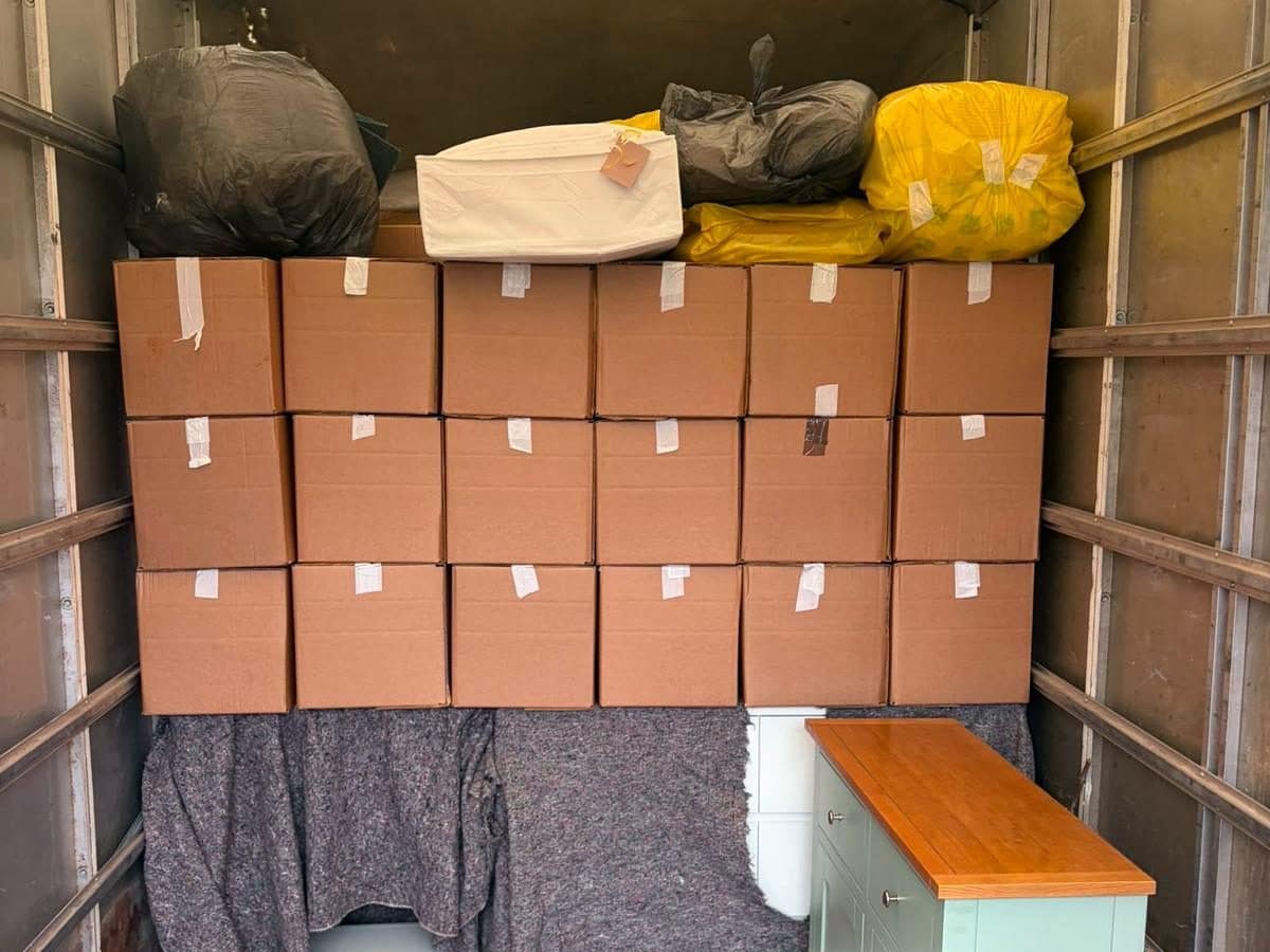 Removal van loaded with a neat wall of boxes above blanket-wrapped furniture