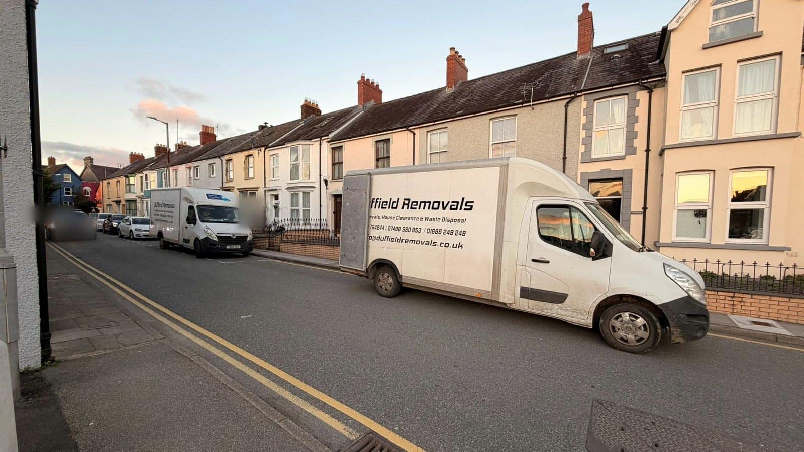 Two Duffield Luton vans parked on a narrow terraced street with double yellow lines