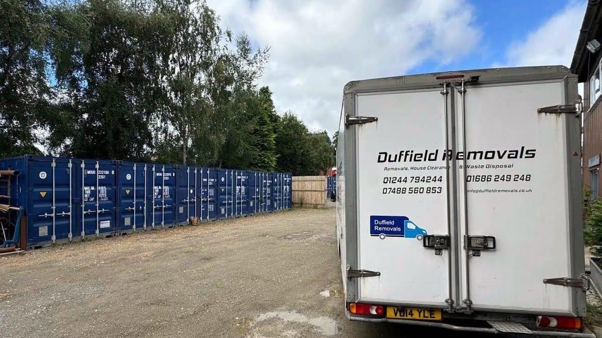 Row of blue 20 ft storage containers at Duffield's Rhayader yard, with a Duffield van