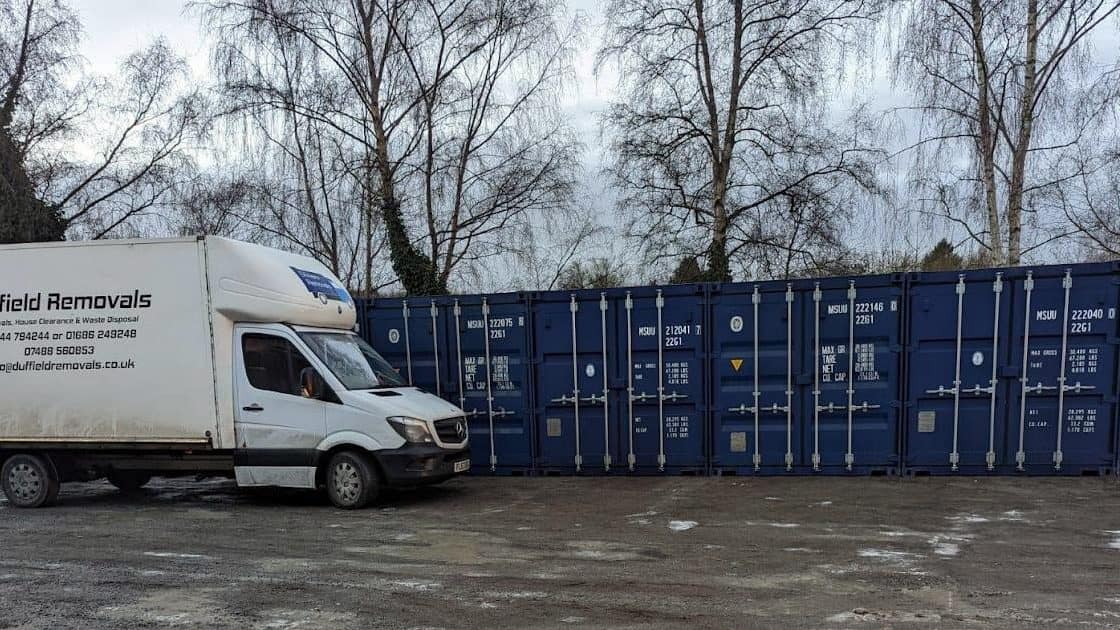 Duffield Luton van beside a row of blue storage containers at Rhayader in winter
