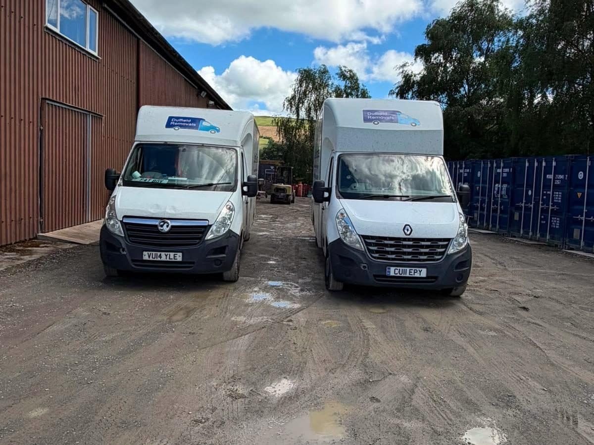 Two Duffield vans at the Rhayader storage yard beside a row of blue containers