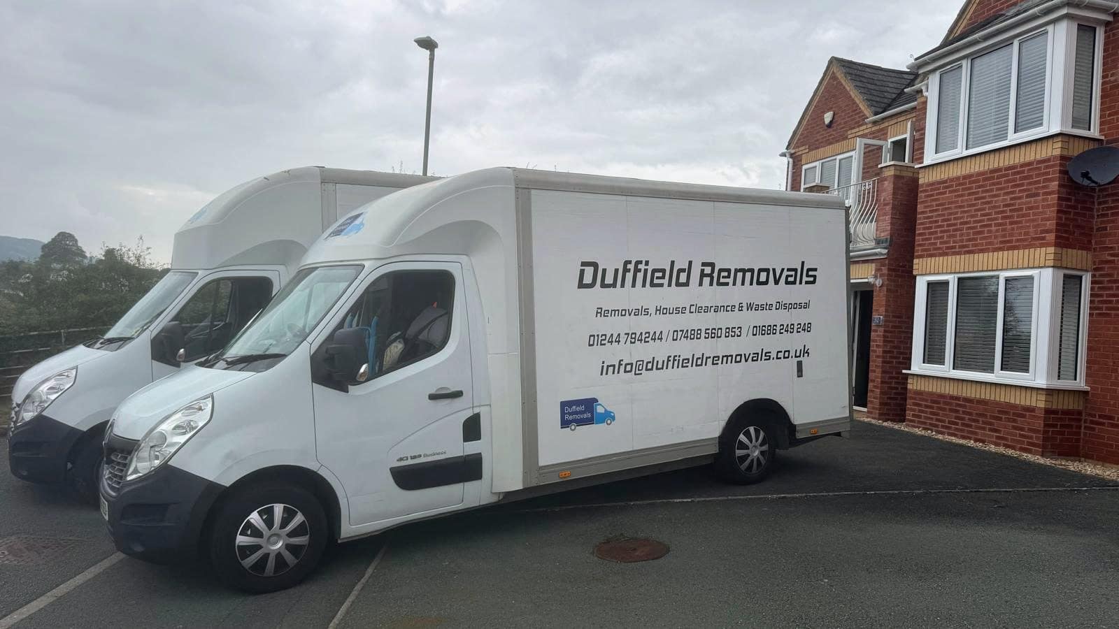 Two liveried Duffield Removals Luton vans parked side by side outside a house on moving day