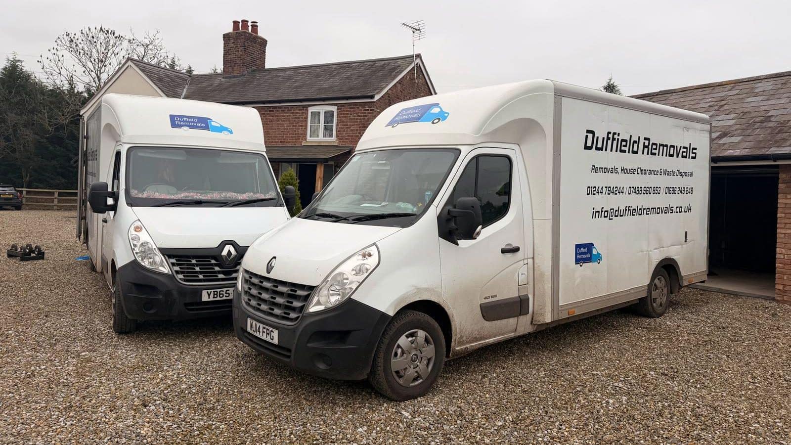 Two Duffield Removals Renault Luton vans on a gravel drive by a red-brick cottage