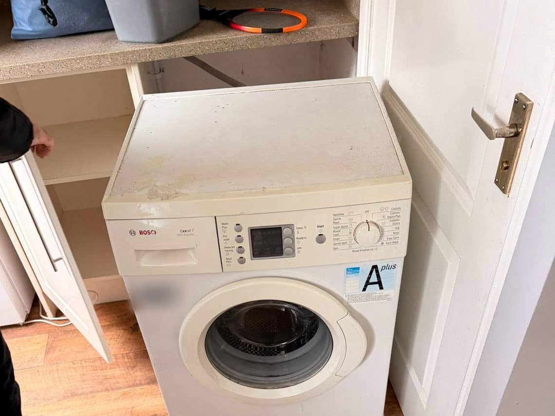 Washing machine pulled out onto floor sliders, ready to move once disconnected