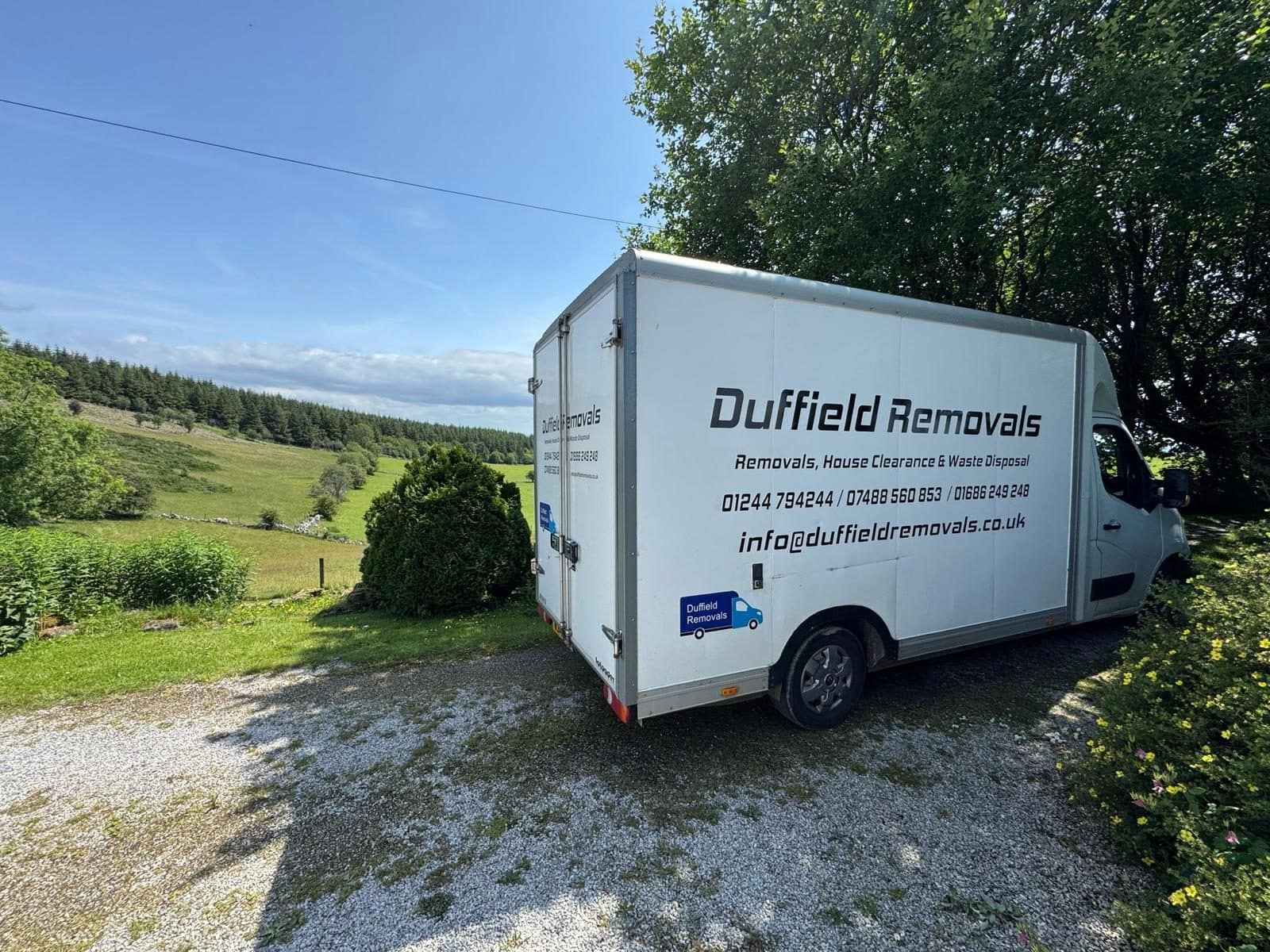 Duffield Removals Luton van with full livery above a valley and conifer forest